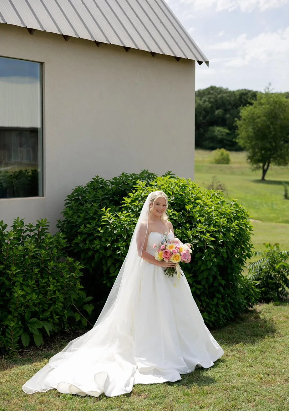 Bride Bailey in her gown by the chapel at Gateley Hill Gardens