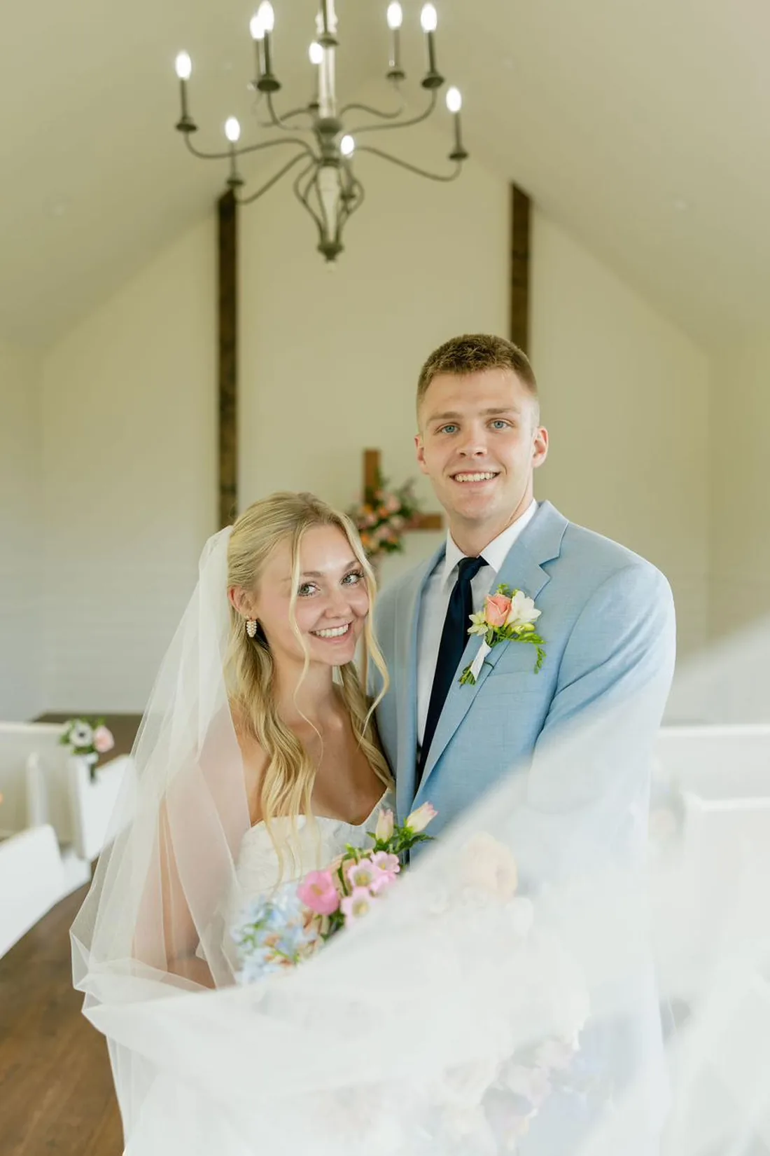 Bride and groom laughing beside the wooden cross inside the chapel at Gateley Hill Gardens