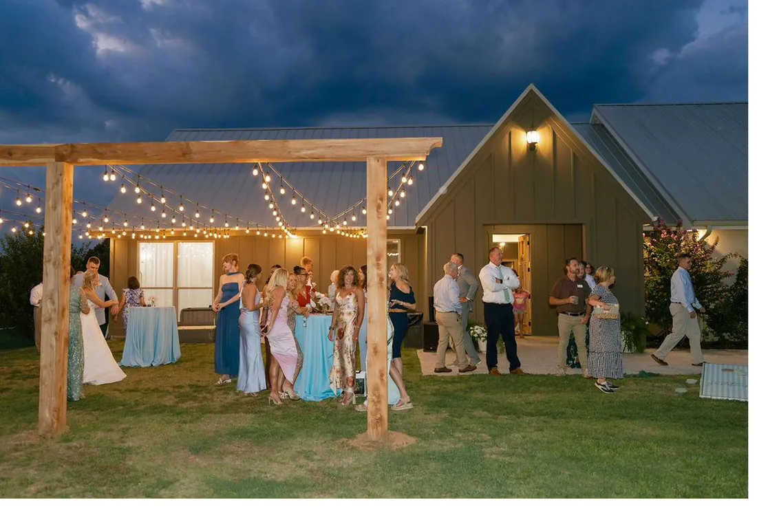Wedding guests celebrating under string lights in the evening at Gateley Hill Gardens