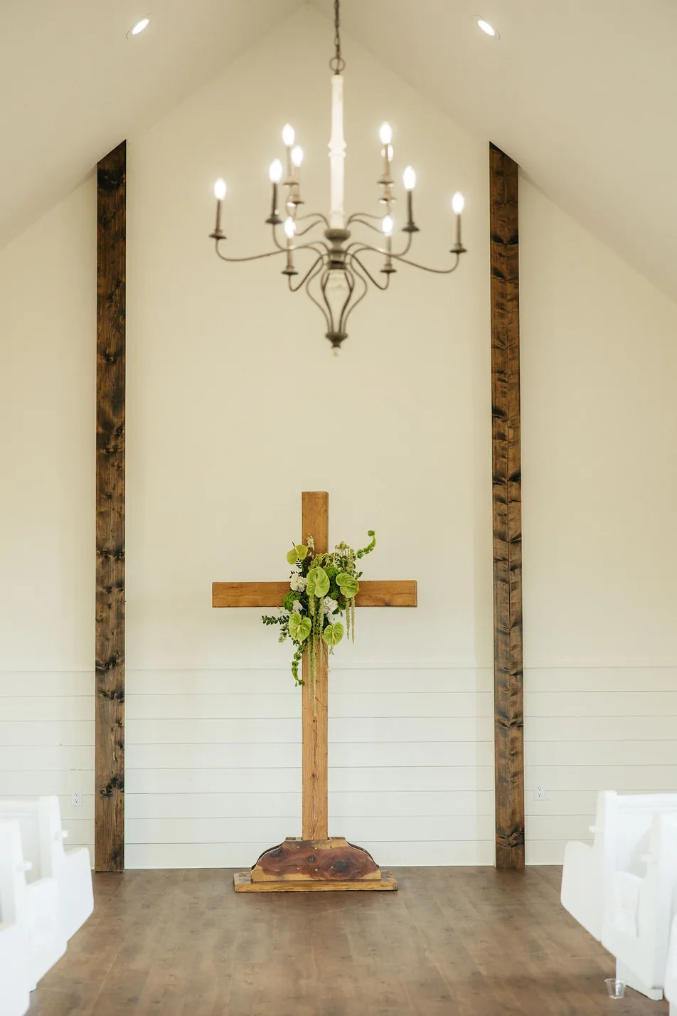 Wooden cross with a fresh floral swag in the chapel at Gateley Hill Gardens