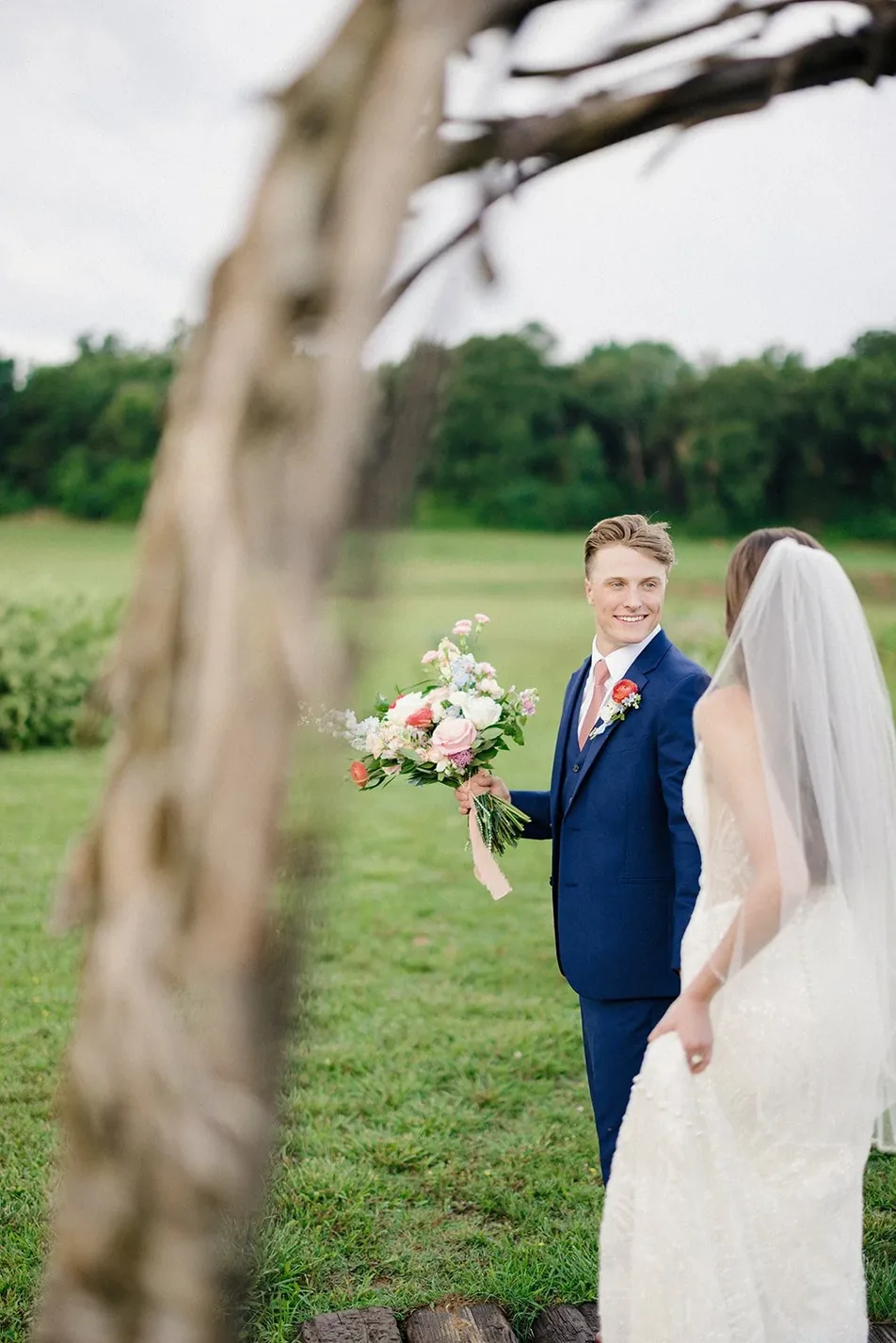 Groom holding the bridal bouquet in the gardens at Gateley Hill Gardens, Dardanelle Arkansas