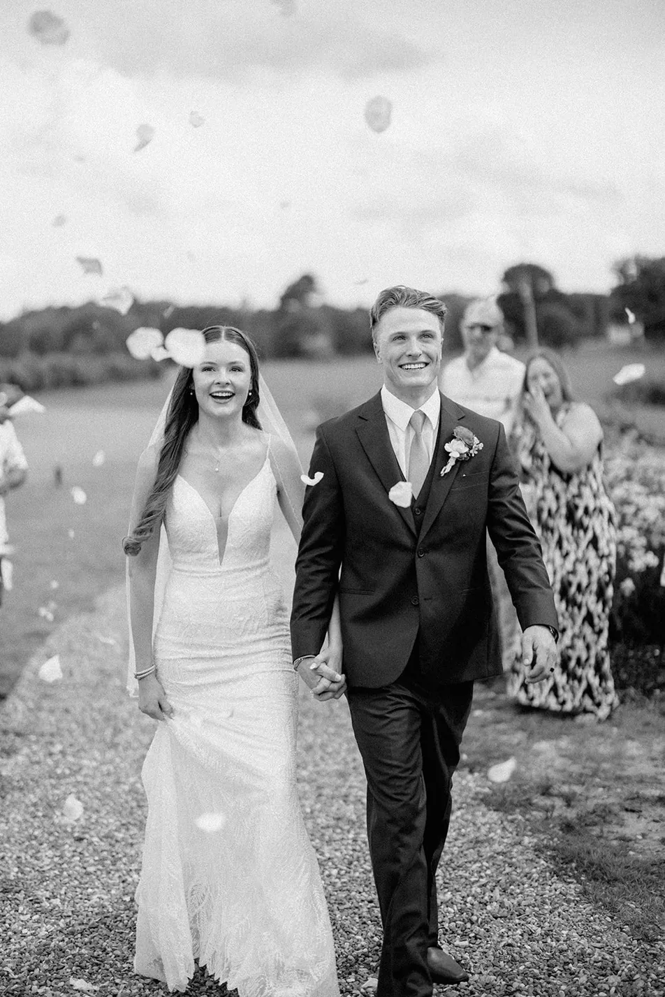 Guests throwing flower petals as a couple leaves their Minimony at Gateley Hill Gardens