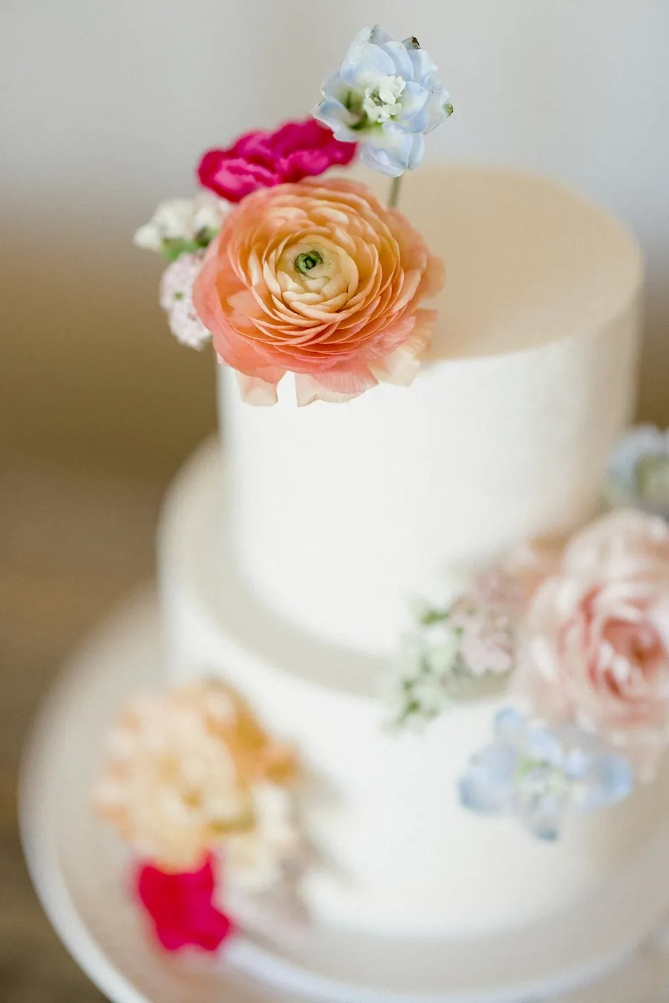 Small white wedding cake topped with fresh garden flowers at Gateley Hill Gardens