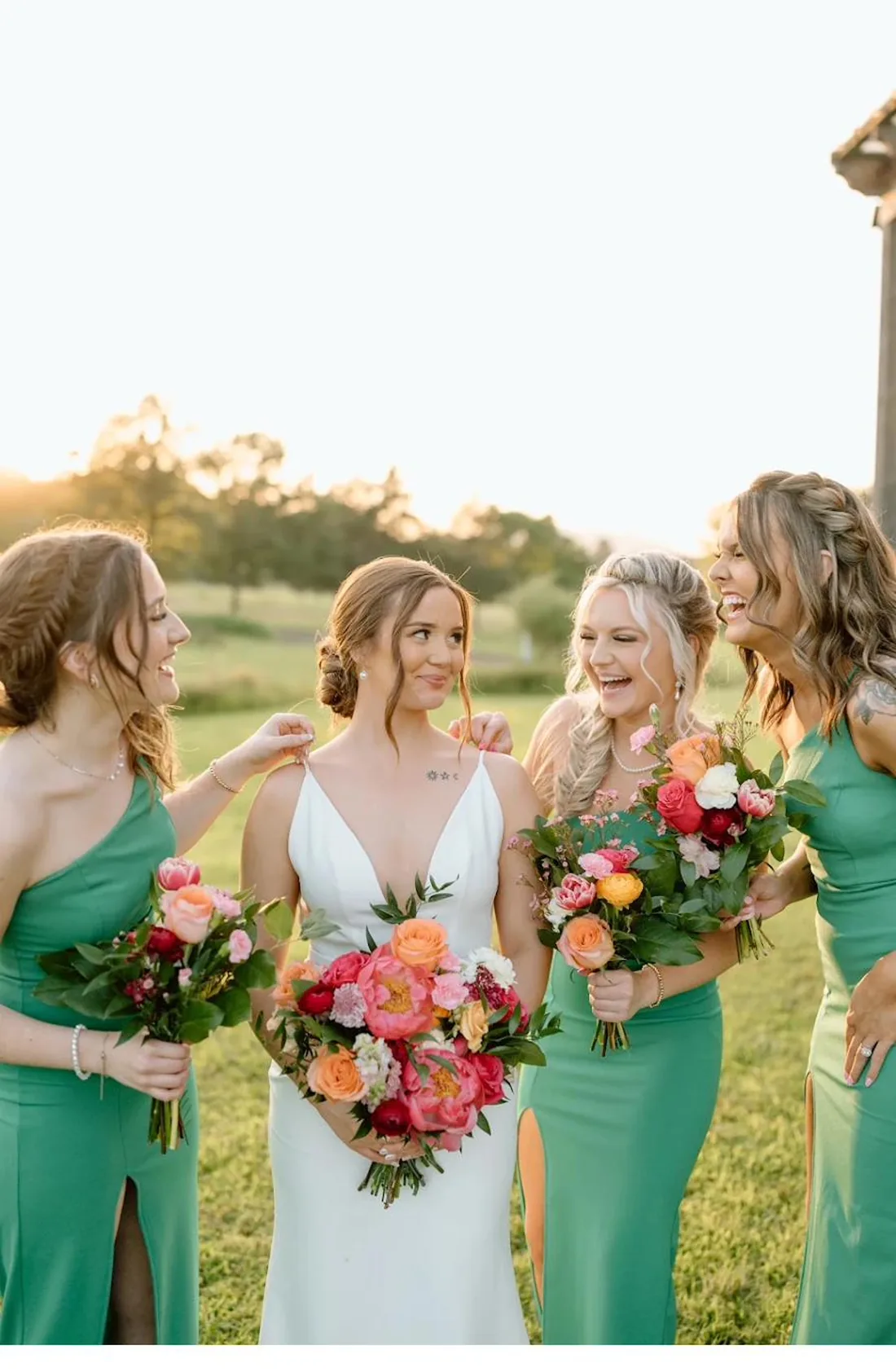 Bride and bridesmaids with bold coral summer florals in golden evening light at Gateley Hill Gardens
